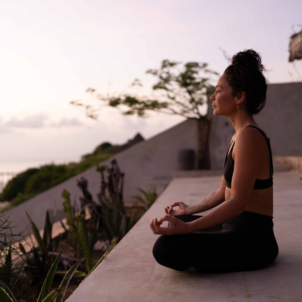 a woman sitting on a ledge with her eyes closed
